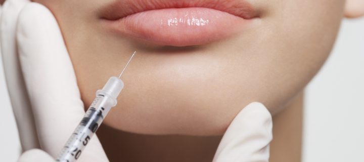 Close up of woman receiving botox injection in lips